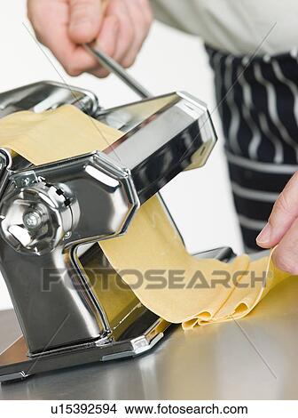 Picture - Fresh Egg Pasta being rolled in a Pasta Machine. Fotosearch