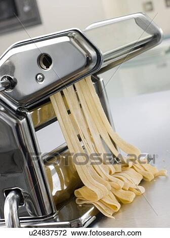 Stock Image - Fresh Egg Tagliatelle Being rolled in a Pasta Machine. Fotosearch