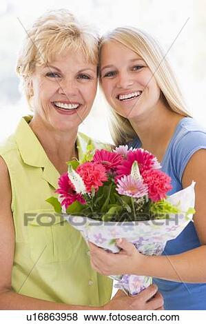 Granddaughter and grandmother holding flowers and smiling View Large Photo Image Stock Photo - Granddaughter and grandmother holding flowers and smiling. Fotosearch