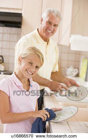 Stock Image - Grandfather And Granddaughter Cleaning Dishes Together. Fotosearch