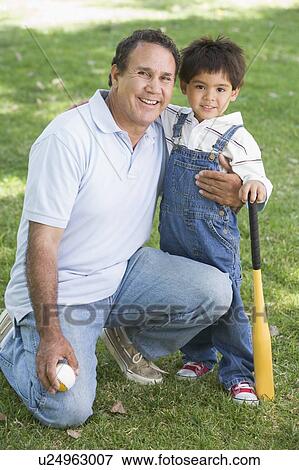 Grandfather and grandson holding baseball bat and smiling View Large Photo Image Stock Photo - Grandfather and grandson holding baseball bat and smiling. Fotosearch
