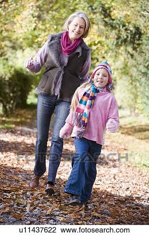 Grandmother and granddaughter walking on path outdoors smiling (selective focus) View Large Photo Image Stock Image - Grandmother and granddaughter walking on path outdoors smiling (selective focus). Fotosearch