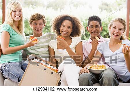 Stock Image - Group Of Teenagers Sitting On A Couch Eating Pizza. Fotosearch