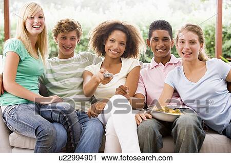 Stock Image - Group Of Teenagers Sitting On A Couch Eating Pizza. Fotosearch