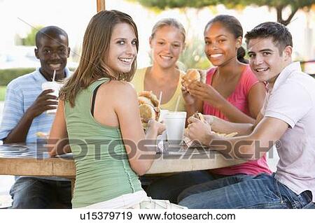 Stock Photo - Group Of Teenagers Sitting Outdoors Eating Fast Food. Fotosearch
