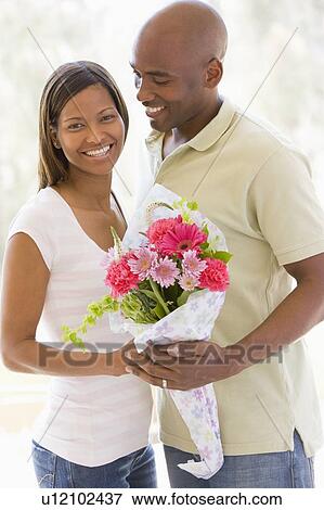 Husband and wife holding flowers and smiling View Large Photo Image Stock Photo - Husband and wife holding flowers and smiling. Fotosearch