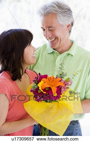 Husband and wife holding flowers and smiling View Large Photo Image Stock Photo - Husband and wife holding flowers and smiling. Fotosearch