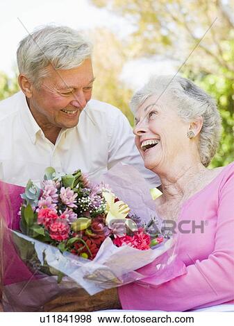 Husband giving wife flowers outdoors smiling View Large Photo Image Stock Photo - Husband giving wife flowers outdoors smiling. Fotosearch
