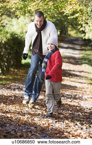 Man and young boy walking on path outdoors smiling (selective focus) View Large Photo Image Stock Image - Man and young boy walking on path outdoors smiling (selective focus). Fotosearch