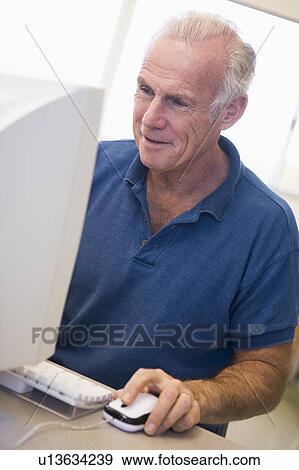 Stock Photo - Man at computer smiling and looking at monitor (high key). Fotosearch