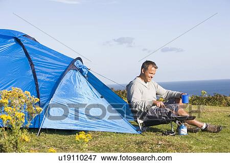 Stock Photo - Man camping outdoors and cooking. Fotosearch