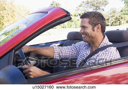 Man driving convertible car smiling View Large Photo Image Stock Image - Man driving convertible car smiling. Fotosearch