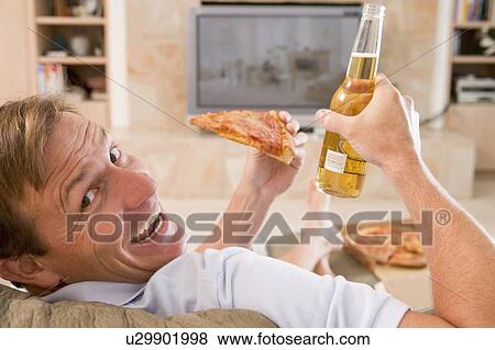 Stock Photo - Man Enjoying Beer And Pizza In Front Of TV. Fotosearch