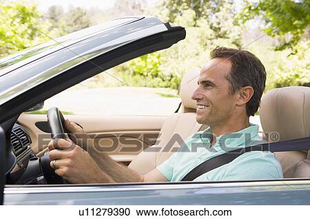 Stock Image - Man in convertible car smiling. Fotosearch