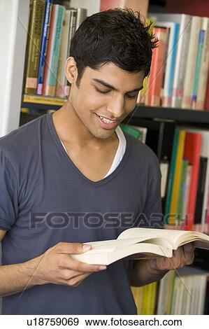 Stock Photo - Man in library reading book. Fotosearch