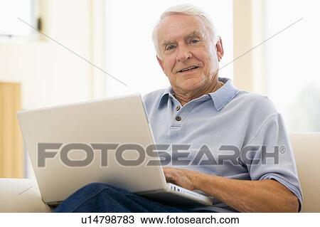 Man in living room with laptop smiling View Large Photo Image Stock Image - Man in living room with laptop smiling. Fotosearch
