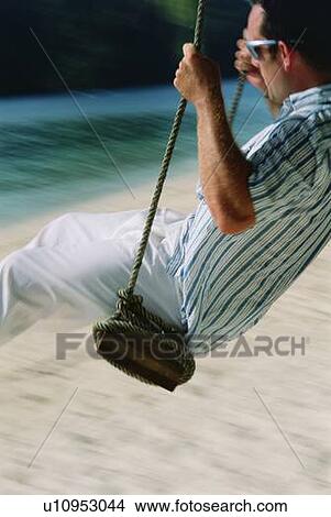 Man on a swing outdoors at the beach (blur) View Large Photo Image Picture - Man on a swing outdoors at the beach (blur). Fotosearch