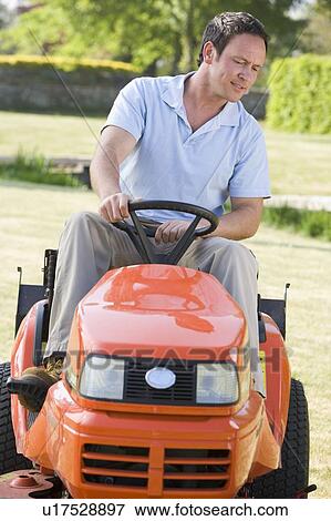Stock Photo - Man outdoors driving lawnmower. Fotosearch