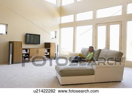 Man reading book in living room smiling View Large Photo Image Stock Image - Man reading book in living room smiling. Fotosearch