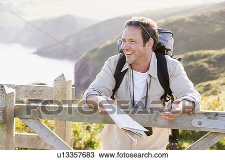 Man relaxing on cliffside path holding map and laughing View Large Photo Image Stock Image - Man relaxing on cliffside path holding map and laughing. Fotosearch