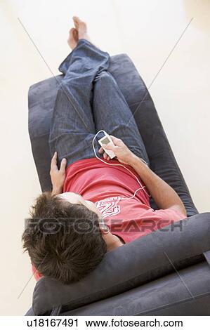 Man sitting in chair listening to MP3 player View Large Photo Image Stock Image - Man sitting in chair listening to MP3 player. Fotosearch