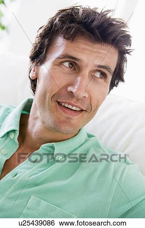 Stock Photograph - Man sitting in living room. Fotosearch