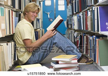 Man sitting on floor in library holding book View Large Photo Image Stock Image - Man sitting on floor in library holding book. Fotosearch