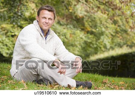 Man sitting outdoors smiling (selective focus) View Large Photo Image Stock Image - Man sitting outdoors smiling (selective focus). Fotosearch