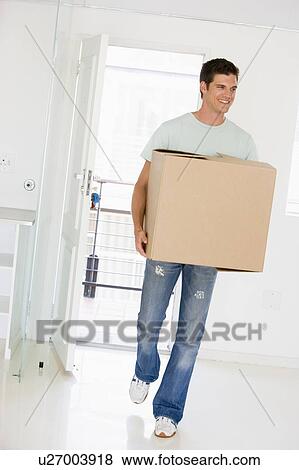 Man with box moving into new home smiling View Large Photo Image Stock Photo - Man with box moving into new home smiling. Fotosearch