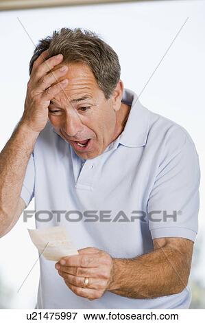 Stock Photo - Man with winning lottery ticket excited and smiling. Fotosearch