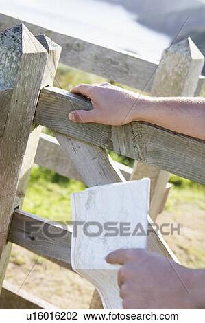 Man's hands on fence holding map View Large Photo Image Stock Image - Man's hands on fence holding map. Fotosearch