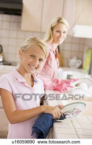 Stock Image - Mother And Daughter Cleaning Dishes. Fotosearch