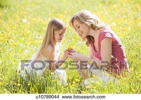 Mother and daughter outdoors holding flower smiling View Large Photo Image Picture - Mother and daughter outdoors holding flower smiling. Fotosearch
