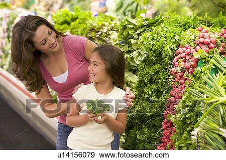 Mother and daughter shopping for broccoli at a grocery store View Large Photo Image Stock Photo - Mother and daughter shopping for broccoli at a grocery store. Fotosearch