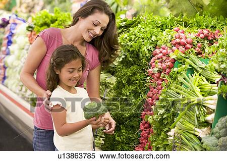 Stock Photography - Mother and daughter shopping for broccoli at a grocery store. Fotosearch
