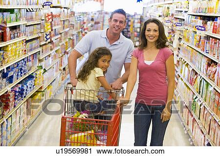 Stock Image - Mother and father with young daughter shopping at the grocery store.. Fotosearch