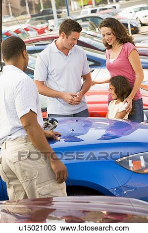 Stock Image - Mother Father and young daughter shopping for a new car. Fotosearch