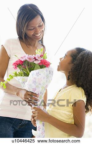 Stock Photography - Mother giving daughter flowers and smiling. Fotosearch