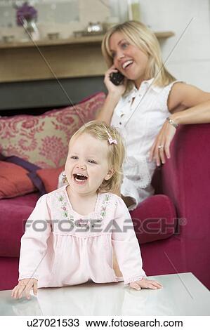 Mother using telephone in living room with baby smiling View Large Photo Image Stock Image - Mother using telephone in living room with baby smiling. Fotosearch