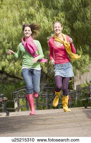 Stock Image - Pair Of Teenage Girls Jogging In Park . Fotosearch