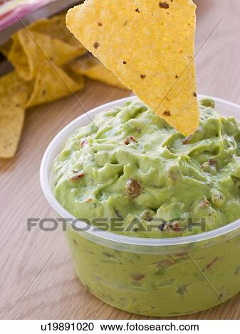 Stock Image - Pot Of Guacamole With A Corn Tortilla Crisp. Fotosearch