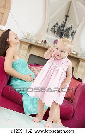 Pregnant mother holding belly in pain with daughter pointing in foreground View Large Photo Image Stock Image - Pregnant mother holding belly in pain with daughter pointing in foreground. Fotosearch