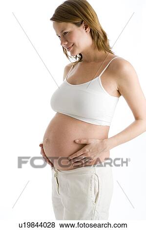 Pregnant woman holding exposed belly smiling View Large Photo Image Stock Photo - Pregnant woman holding exposed belly smiling. Fotosearch