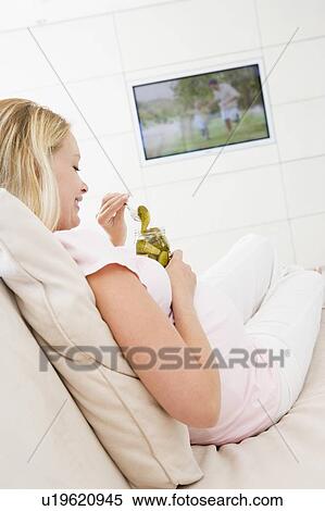 Pregnant woman watching television and eating pickles smiling View Large Photo Image Stock Photography - Pregnant woman watching television and eating pickles smiling. Fotosearch