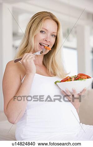 Stock Image - Pregnant woman with bowl of salad smiling. Fotosearch
