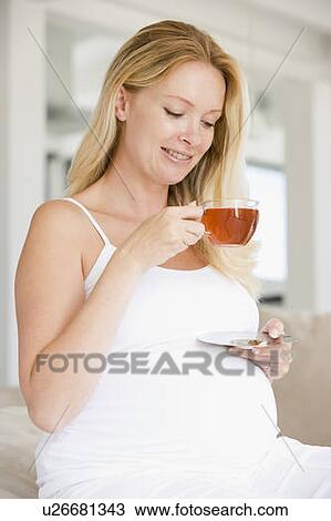 Stock Image - Pregnant woman with cup of tea smiling. Fotosearch