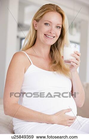 Pregnant woman with glass of milk smiling View Large Photo Image Stock Photo - Pregnant woman with glass of milk smiling. Fotosearch