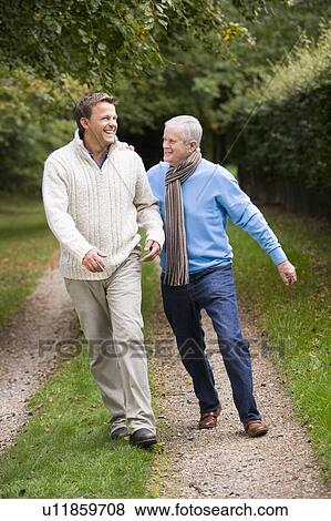 Stock Photo - Senior father and son walking on path outdoors smiling. Fotosearch
