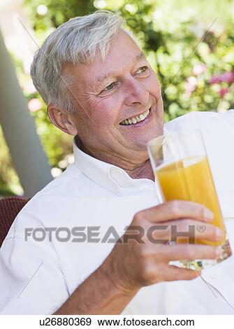 Senior man sitting outdoors with a glass of orange juice View Large Photo Image Stock Photo - Senior man sitting outdoors with a glass of orange juice. Fotosearch