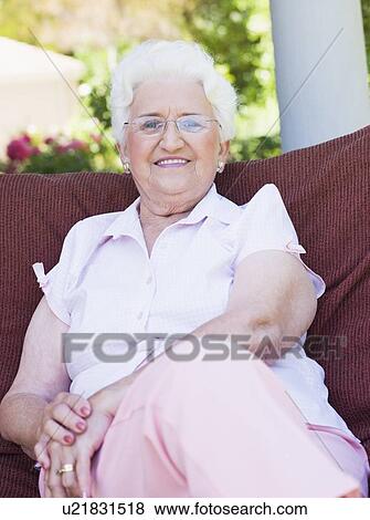 Stock Photo - Senior woman sitting outdoors on a chair. Fotosearch